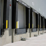 Grey industrial loading bays with dock levellers and roller doors, showing the bridge-the-gap design to support safe loading and unloading.