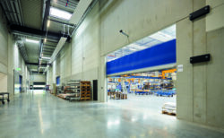High Speed Doors in an industrial warehouse with a blue fast-acting door, concrete walls and steel fixtures, supporting constant workflow.