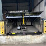 Loading Bays leveller installed in an industrial loading bay, with steel deck, yellow hydraulic components and safety indicators in view.