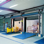 Loading bays with a dock leveller in a blue industrial warehouse, showing steel loading bay equipment and safe bridging between dock and vehicle.