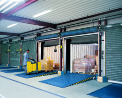 Loading bays with a dock leveller in a blue industrial warehouse, showing steel loading bay equipment and safe bridging between dock and vehicle.